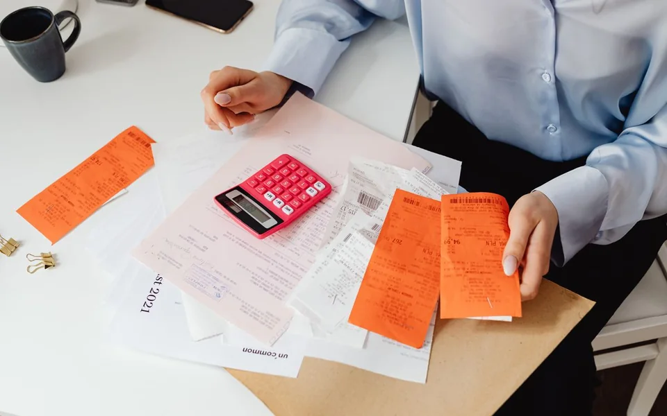 Person sorting paper receipts beside a calculator