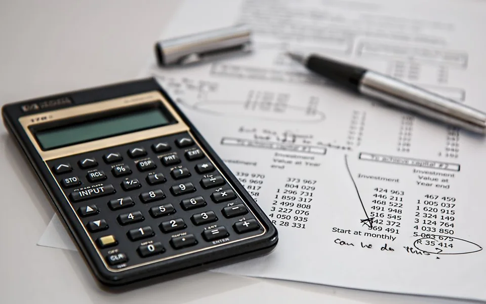 Calculator and pen on printed financial records
