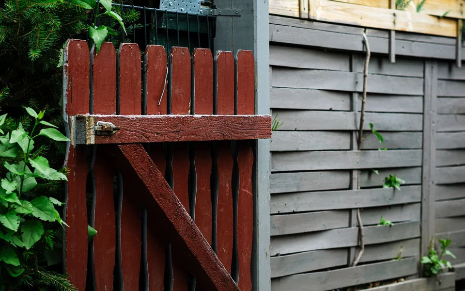 Red wooden garden gate beside a horizontal wood fence