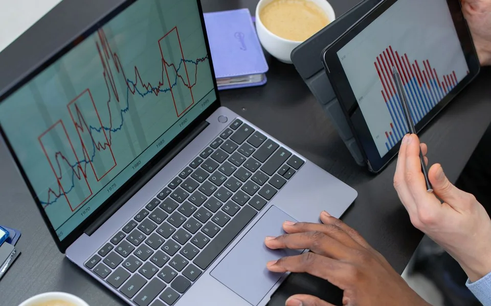 People reviewing charts on a laptop and tablet side by side